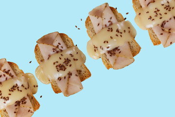 Toasted bread with ham, yellow cheese and flax seeds with a green, purple and blue background.