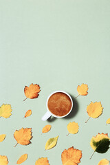 Fototapeta na wymiar Autumn composition with cup of coffee and autumn leaves. Cozy atmosphere and hot coffee with milk