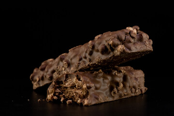 Soft bar crispy wafer with nuts and coated chocolate layer on black background