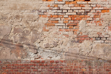 A fragment of an old, dingy brick wall along with remnants of plaster.