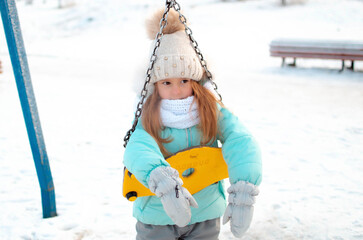 Charming little girl on swing in snowy winter