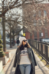 Fototapeta premium Elegant girl walk in a winter city. Woman in a white knited sweater. Beautiful lady with dark hair.
