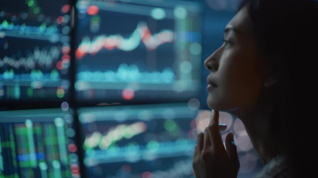 Close Up Portrait of Financial Analyst Working on Computer with Multi-Monitor Workstation with Real-Time Stocks, Commodities and Exchange Market Charts. Businesswoman at Work in Investment Agency.