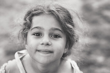 Black and white Portrait of smiling cute little girl at summer park. Happy child looking at the camera