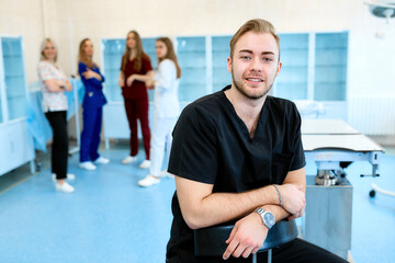 A horizontal portrait of a young hansdsome male doctor wearing a black scrub.