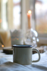 Open book, warm drink and lit candles. Hygge at home. Selective focus.