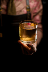 great view of flower petal decorating cold cocktail in glass held by male hand