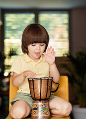 Little boy playing traditional african djembe drum at home. Child musical education and development