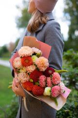 Woman in grey coat holding beautiful bouquet of autumn flowers.