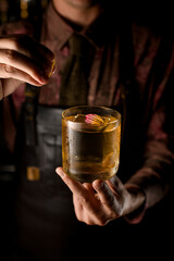 gorgeous view of glass with cocktail decorating by flower petal which hand of man accurate holds and sprinkles