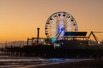 The Ferris wheel of the famous Santa Monica Pier at sunset on the beach in Los Angeles