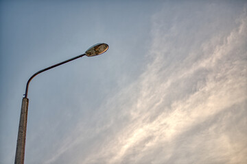 Old street lamp with blue sky and clouds in background.