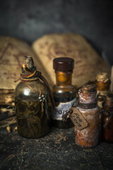Magic potions in bottles, ancient books and witchery herbs on wooden background, Halloween theme
