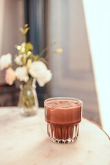 Glass of cold chocolate milk drink on a white marble table.
