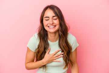 Young caucasian woman isolated on pink background laughs out loudly keeping hand on chest.