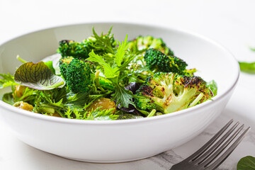 Green salad with grilled broccoli and olives in white bowl. Vegan food, detox, healthy food concept