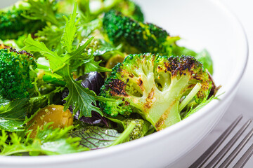 Green salad with grilled broccoli and olives in white bowl. Vegan food, detox, healthy food concept