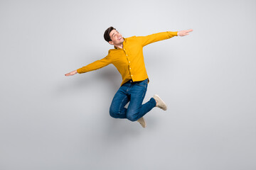 Fototapeta na wymiar Full length body size view of attractive cheerful man jumping flying like plane isolated over grey color background