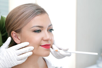 Young woman having permanent makeup on her lips at the beauticians salon.