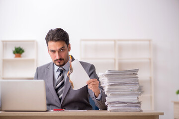 Naklejka premium Young male employee unhappy with excessive work in the office