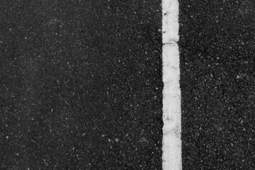 Abstract view of a road in a park with white road lines crossing straight on the right side of the image. Can be used in traffic or background applications.