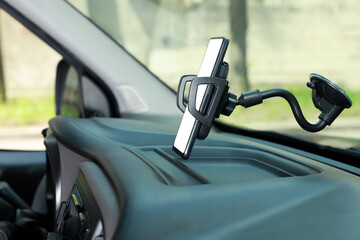 Car holder with modern mobile phone on windshield of automobile