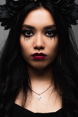 Fototapeta premium brunette asian woman with vampire halloween makeup looking at camera isolated on grey