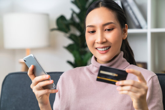 Beautiful Asian Woman Holding Credit Card And Using Smartphone For Shopping Online With Payment On Internet Banking.