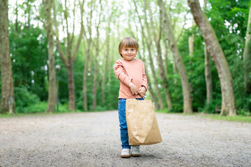 Little boy carrying a paper bag after a successful shopping i a moll. Shopping with children during sales. Black friday concept.