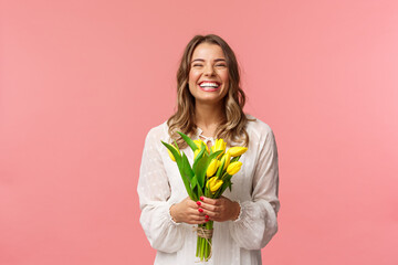 Holidays, beauty and spring concept. Portrait of happy excited charming blond girl receive flowers,...