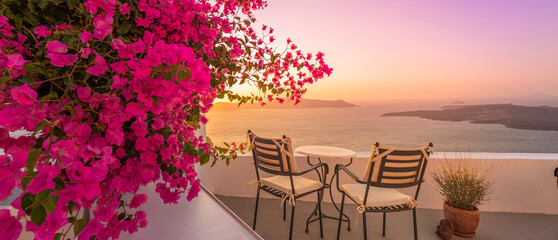 Summer sunset vacation scenic of luxury famous Europe destination. White architecture in Santorini, Greece. Stunning travel scenery with pink flowers chairs, terrace sunny blue sky. Romantic street - obrazy, fototapety, plakaty