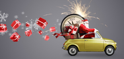 Christmas is coming. Santa Claus on toy car delivering New Year 2022 gifts and countdown clock at gray background with fireworks
