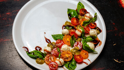 Fototapeta na wymiar Caprese salad. Healthy meal with cherry tomatoes, mozzarella balls, spices, fresh rocket and basil.