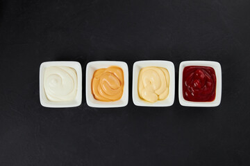 different sauces in small white plates, ketchup, mayonnaise, mustard, garlic