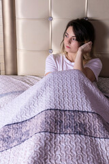 woman sitting in bed pensive staring blankly