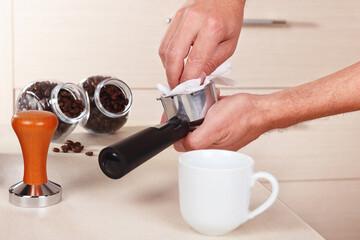 Fototapeta na wymiar Barista wipes holder before making espresso above table.