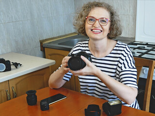 woman photographer making her blog about photo and video camera in kitchen, lens and flash...