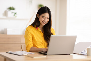 Entrepreneur beautiful business asian young woman wear yellow shirt work online with laptop at home.Freelance woman working online sale marketing at home.Small Business Startup concept.Tracking Shot