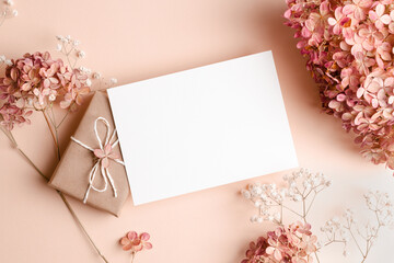 Invitation or greeting card mockup with gift box, hydrangea and gypsophila flowers decorations....