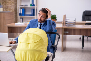 Young male employee looking after new born at workplace