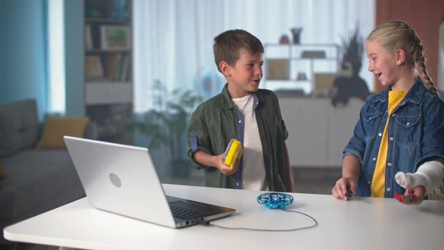 children entertainment, active kids with tools go to the table to repair mini quadcopter that is connected to laptop via a USB cable