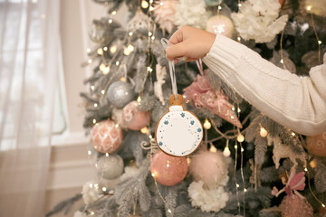 Kid decorates Christmas tree with gingerbread at home. Happy, warm lifestyle. Winter comfort. New Year's holidays. Place for text on gingerbread