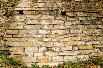 old stone wall of yellow brick with holes