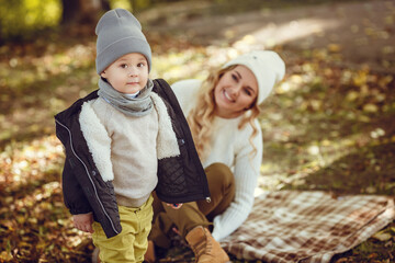 mother and son are walking outdoors on a sunny autumn day