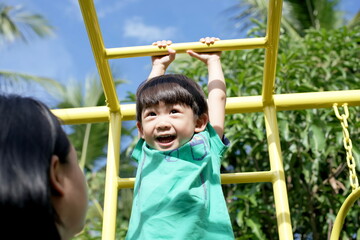 Fototapeta premium Little asian boy climbing on monkey bar at outdoor playground