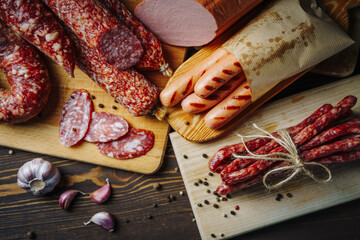 Various types of meat and sausages on wooden table, served on board, closeup. Top view.