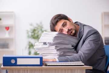 Naklejka premium Young male employee and too much work in the office