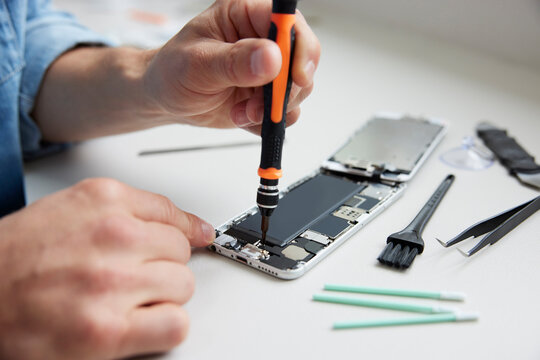 Close Up Of Man Trying To Fix Mobile Phone Rather Than Buying New Product Sustainable Lifestyle
