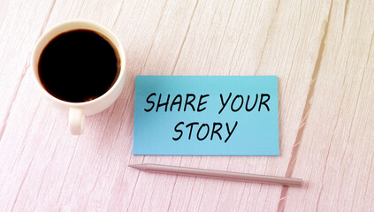 SHARE YOUR STORY text on the blue sticker with cofee and pen