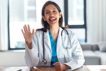 Beautiful female doctor looking at camera while working sitting in the consultation.